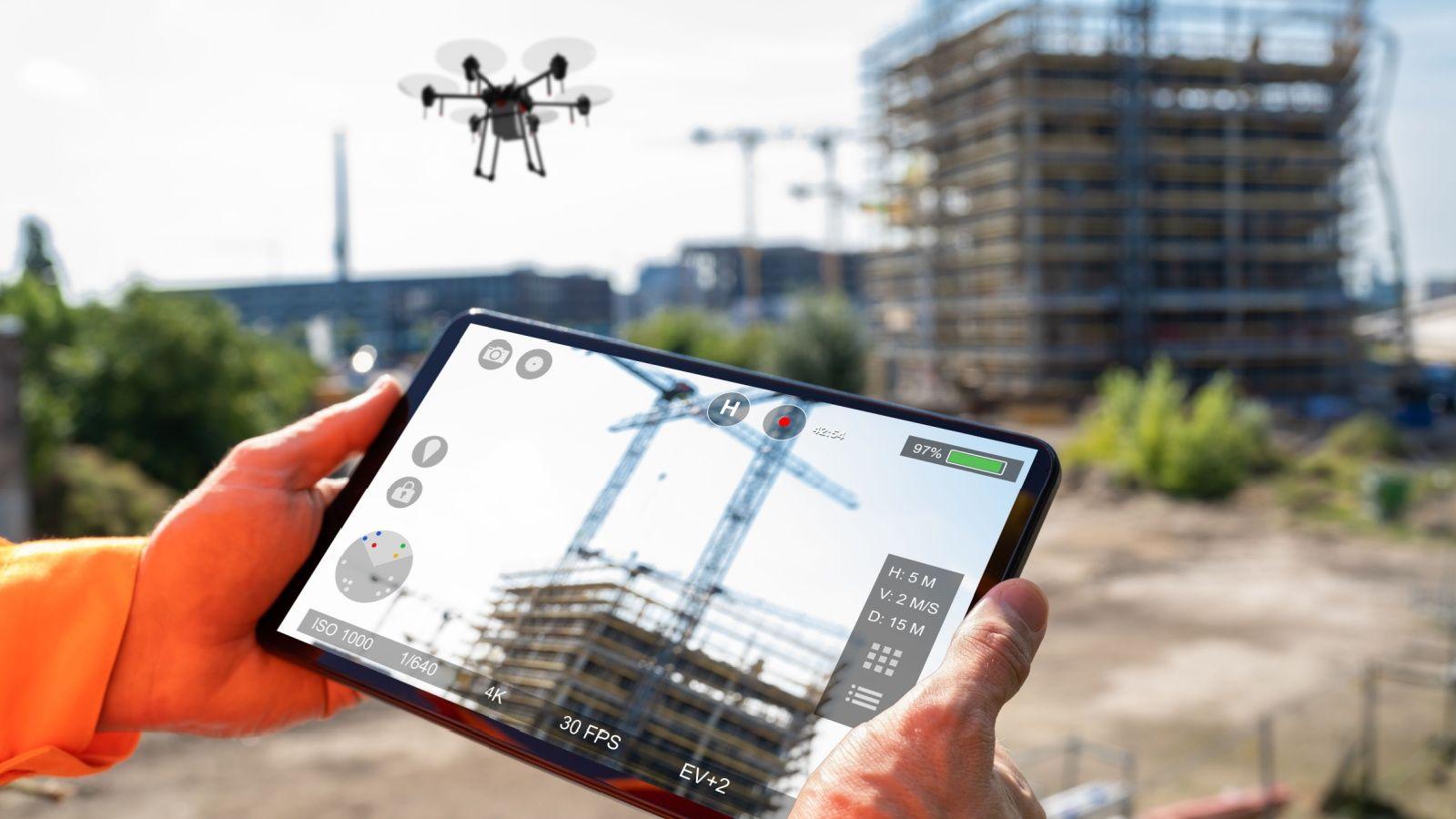 a flying drone transmitting video to a tablet on a construction site