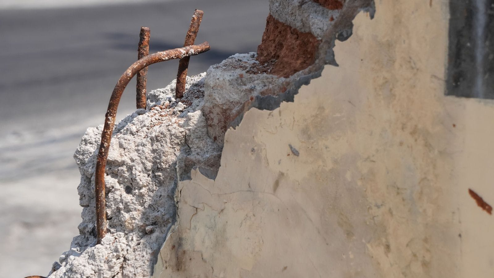 an image of rusting rebar sticking out of corroded concrete on a building facade