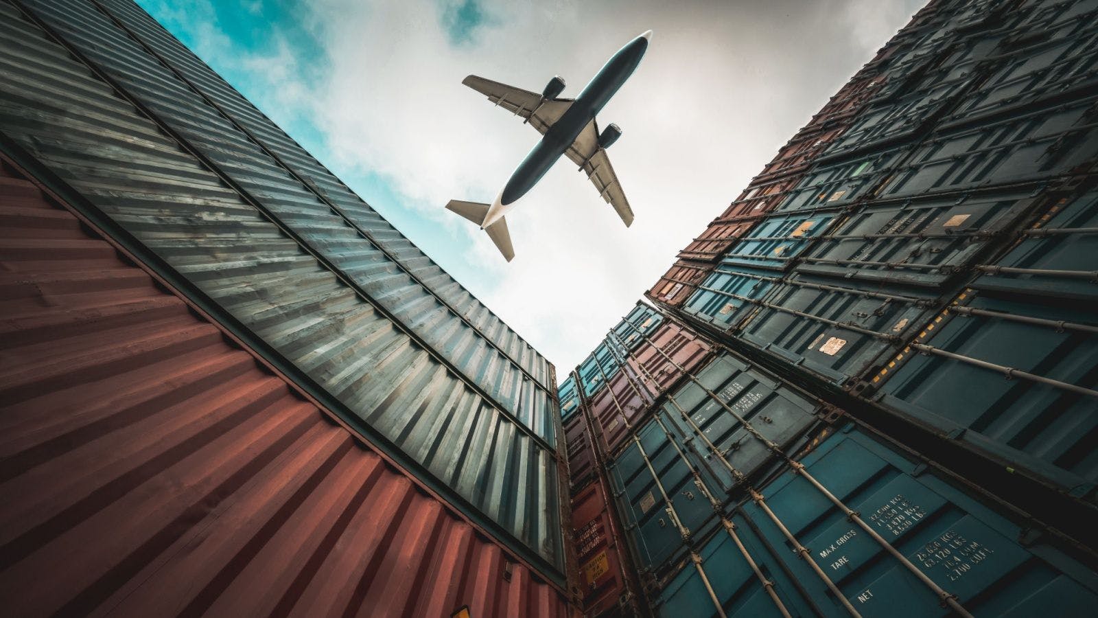an airplane flying over supply-chain shipping crates 