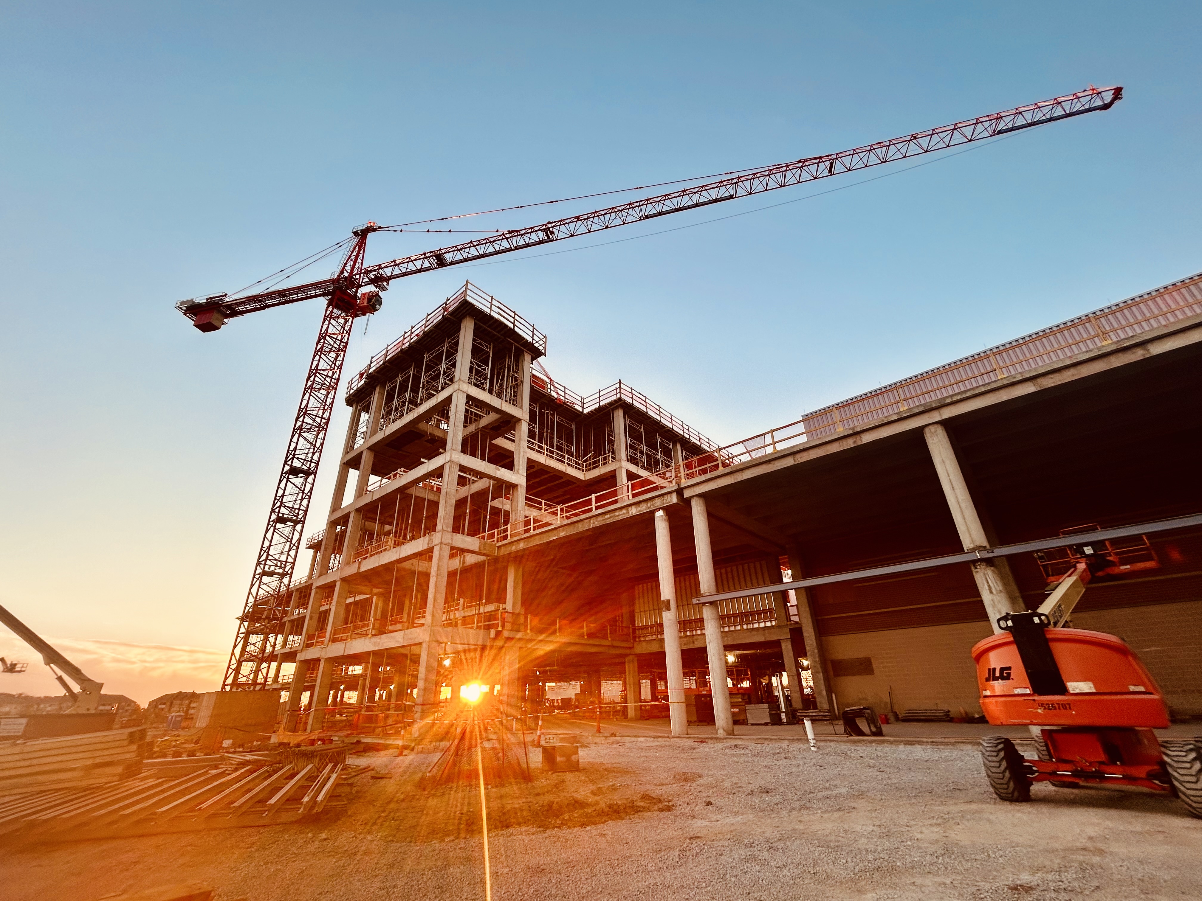a construction site with a large crane and a nearly built building during the sunset.