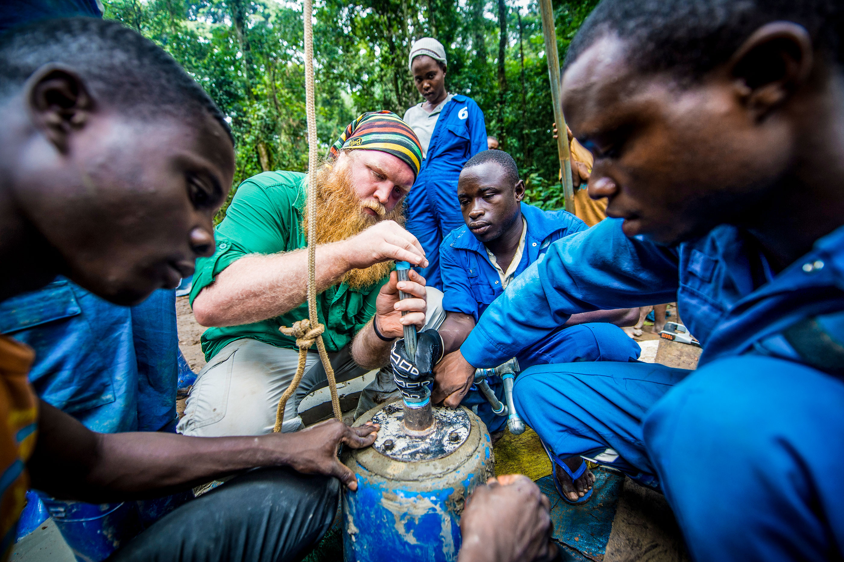 a man helping a group of indigenous people in East Africa build a fresh-water well.