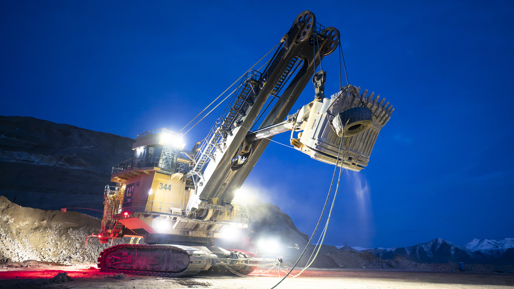 an excavator working a jobsite at night, lit up by stadium lights
