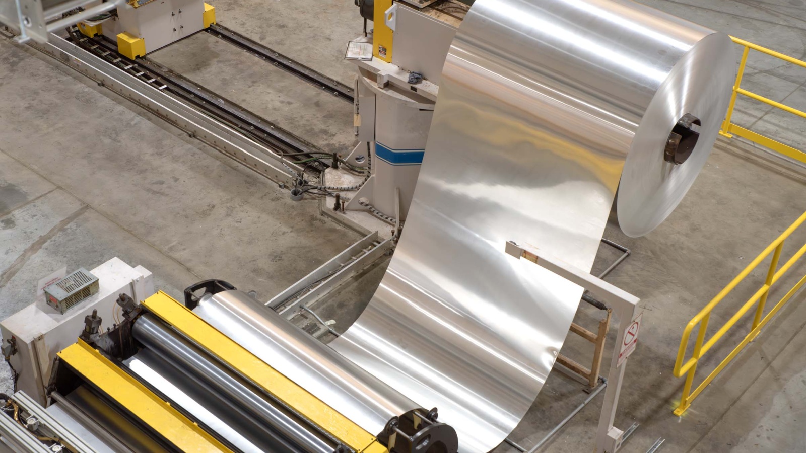 an aerial image of a machine rolling sheets of aluminum at an aluminum can manufacturing plant