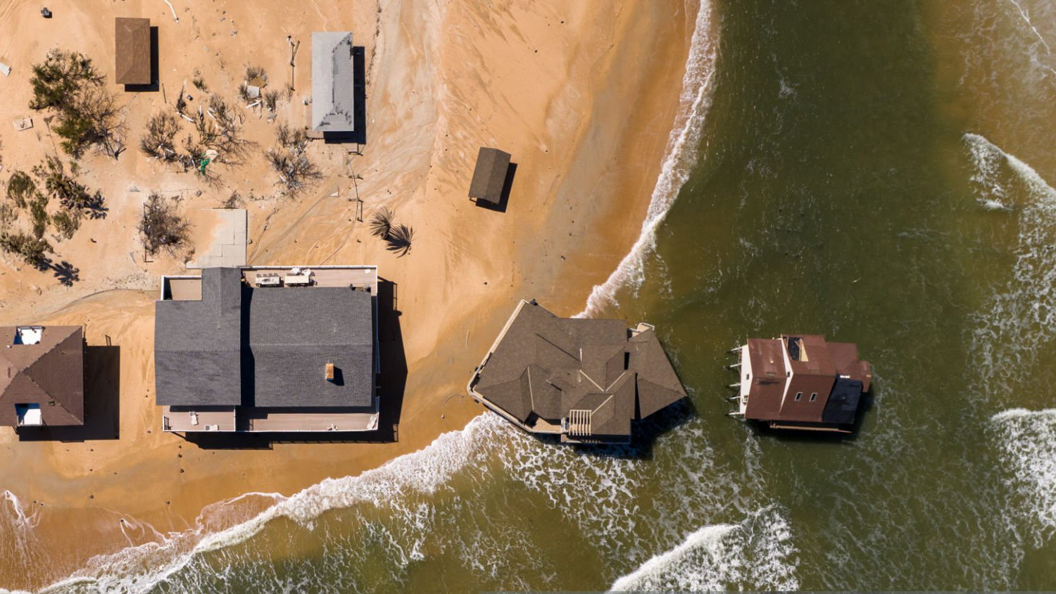 houses falling into the ocean after flooding due to a storm