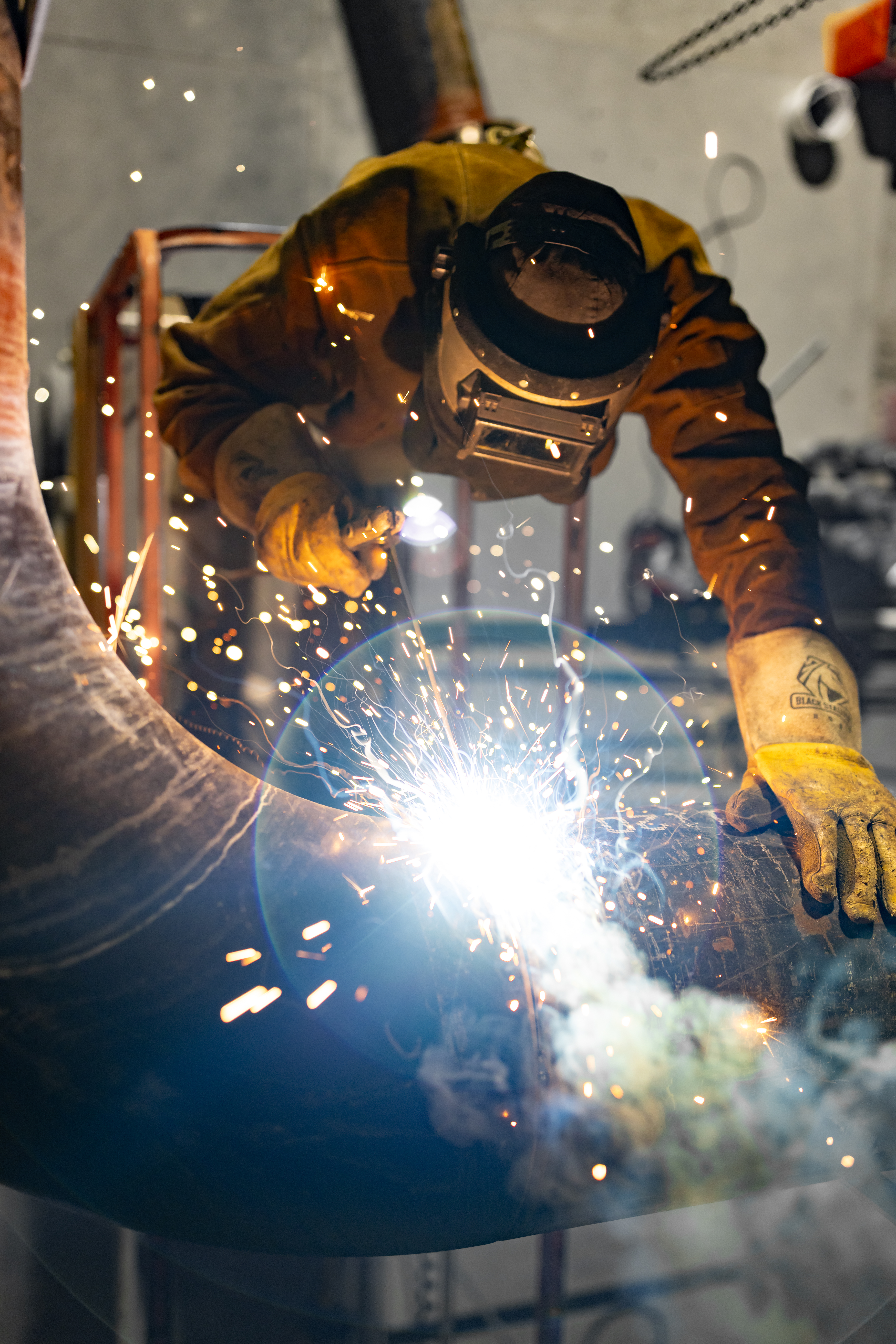 a welder working on a pipe with a welding tool that is creating sparks 