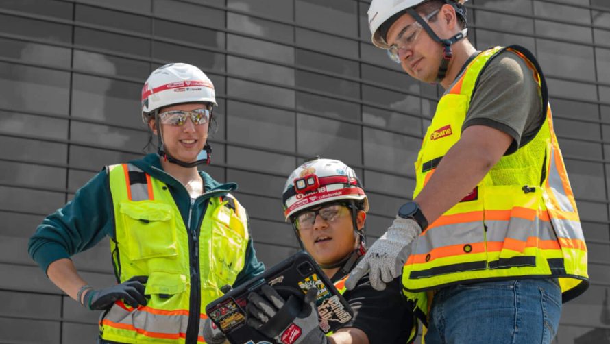 2 male and one female construction workers looking at a tablet