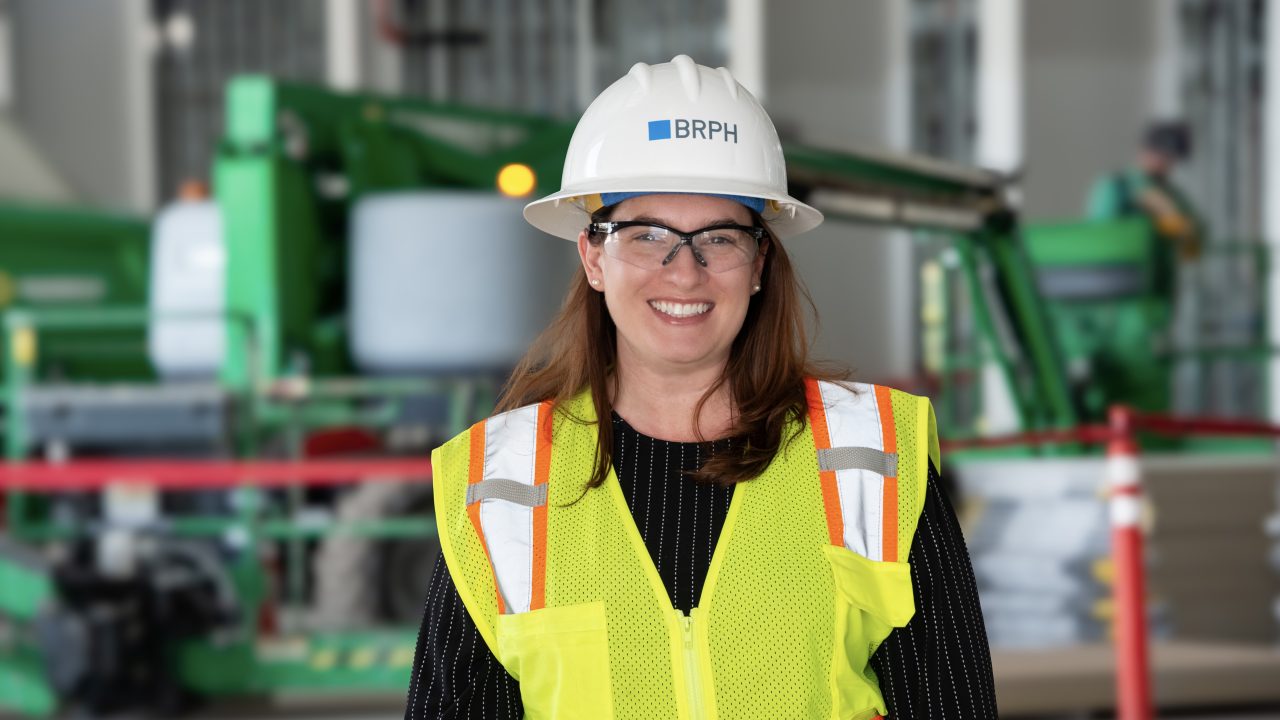 Jennifer Lyon, senior project manager at BRPH wearing a white construction hat and yellow safety vest.