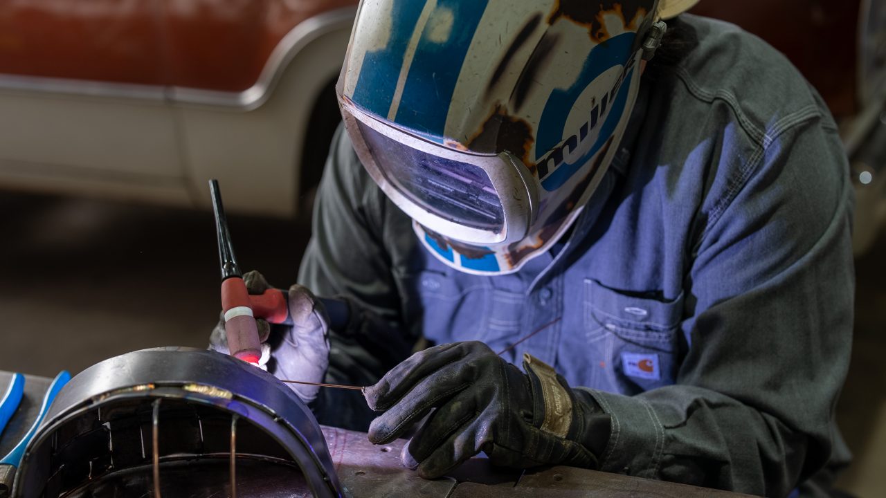 Josh Welton, wearing a welding mask while working on a fully welded construction hard hat for Sache Construction's Hard Hats for Detroit annual art auction.