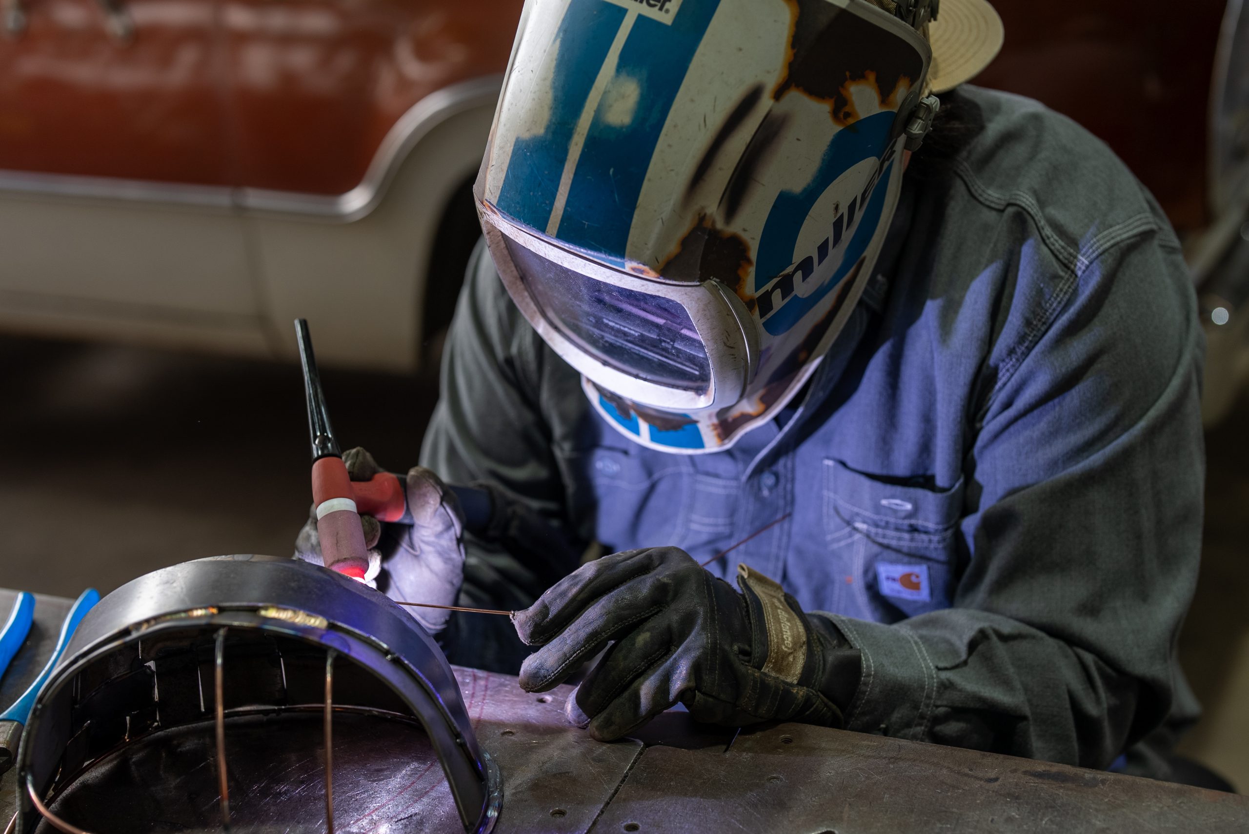 JoshWeltonHardHatsforDetroit101725_DSC01853 Josh Welton, wearing a welding mask while working on a fully welded construction hard hat for Sache Construction's Hard Hats for Detroit annual art auction.