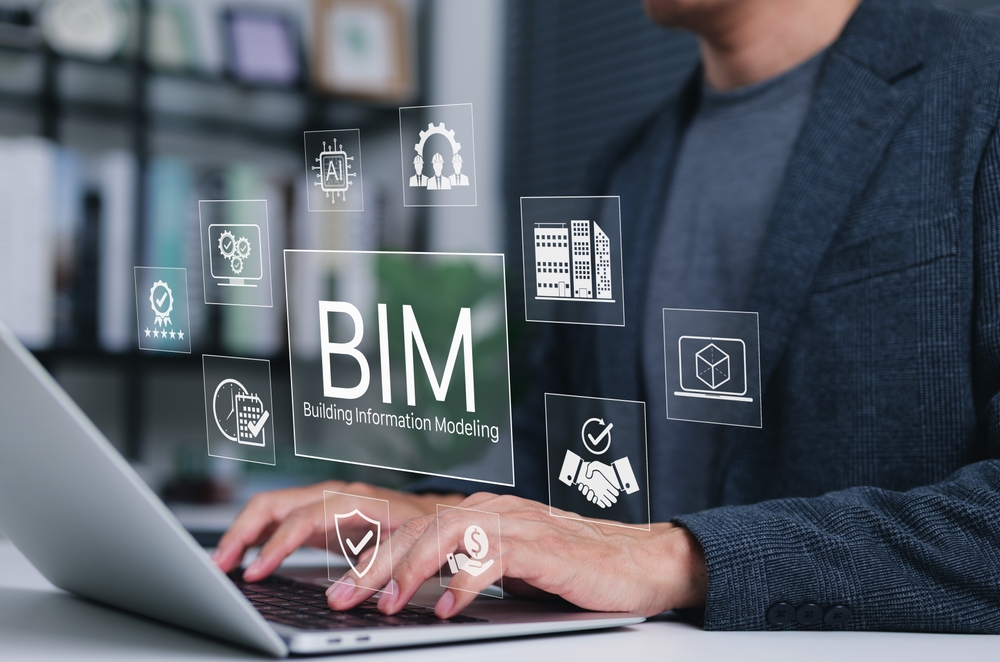 A person in a gray blazer types on a laptop while a glowing digital interface labeled ‘BIM, Building Information Modeling’ floats above the keyboard, surrounded by icons for a building, a 3D cube on a monitor, AI, a handshake, a calendar and clock, a shield with a checkmark, a gear with workers and a dollar sign in a hand.